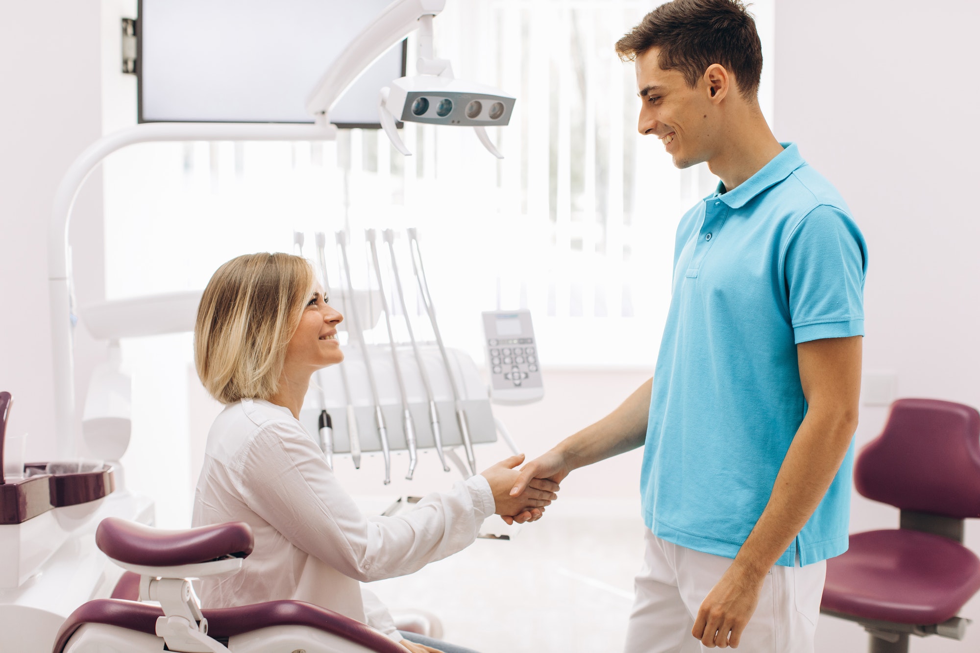 The dentist consults with his female patient sitting in a dental chair